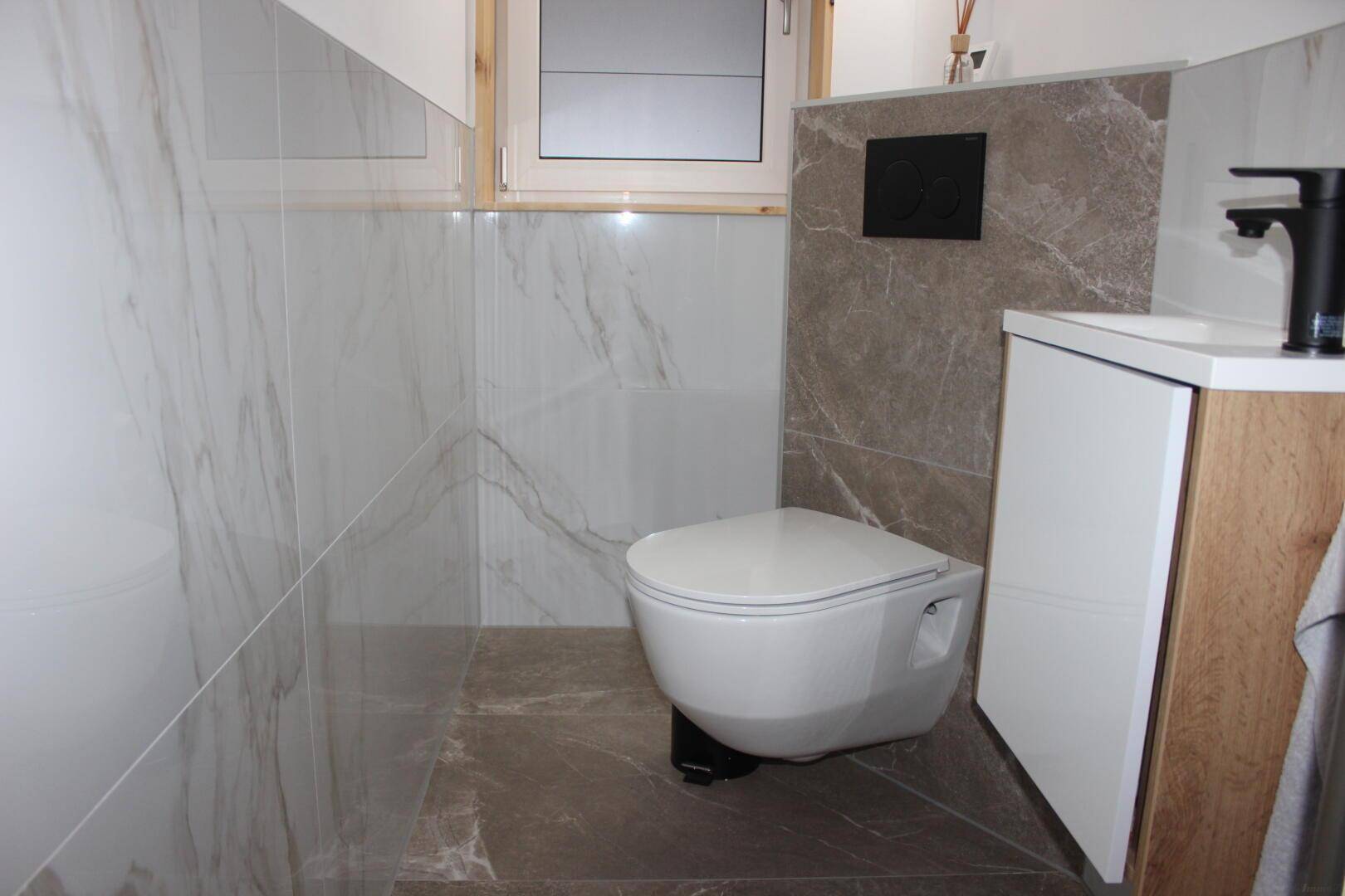 Kleines, modernes WC mit Wand-WC, Waschtisch und stilvollen Fliesen an den Wänden.