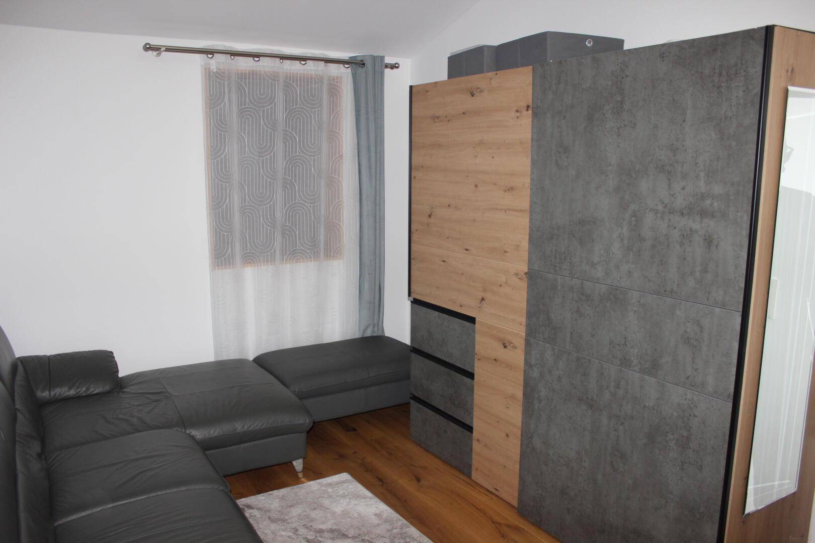 Gemütliches Schlafzimmer mit Sofa, Schrank und Holzboden, ideal als Gästezimmer.