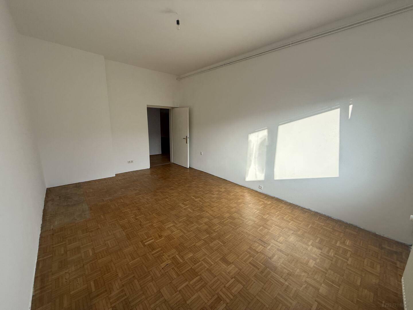Großes Zimmer mit Parkettboden und viel Tageslicht, bereit für neue Einrichtungsideen.