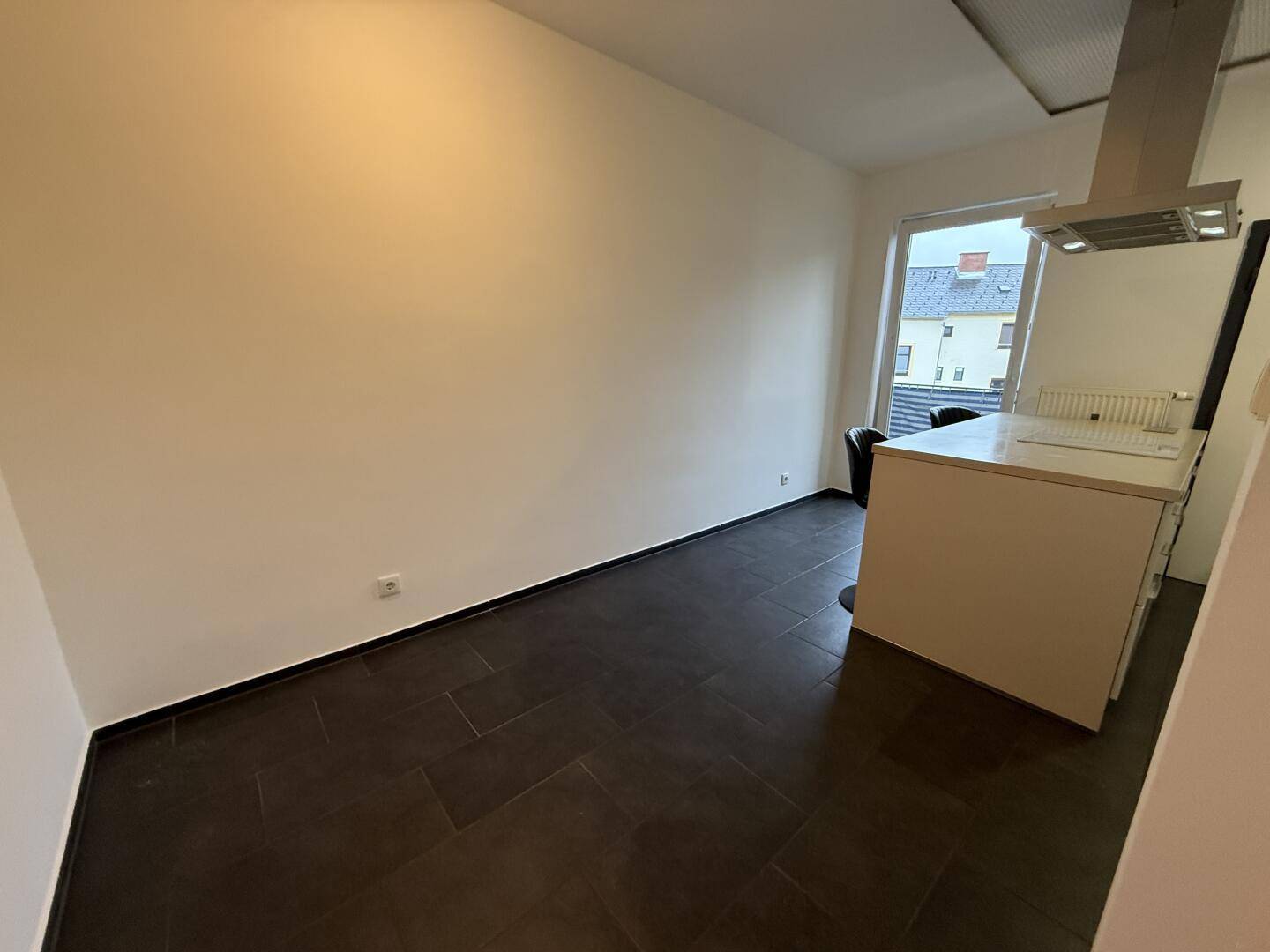 Moderne Küche mit dunklen Fliesen und Dunstabzugshaube, bereit für die Installation von Geräten.