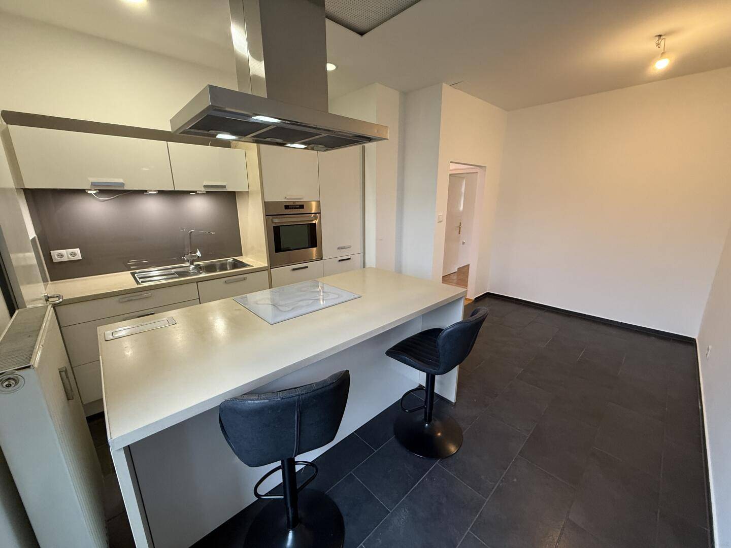 Moderne Einbauküche mit Kochinsel, Induktionskochfeld und integriertem Backofen.