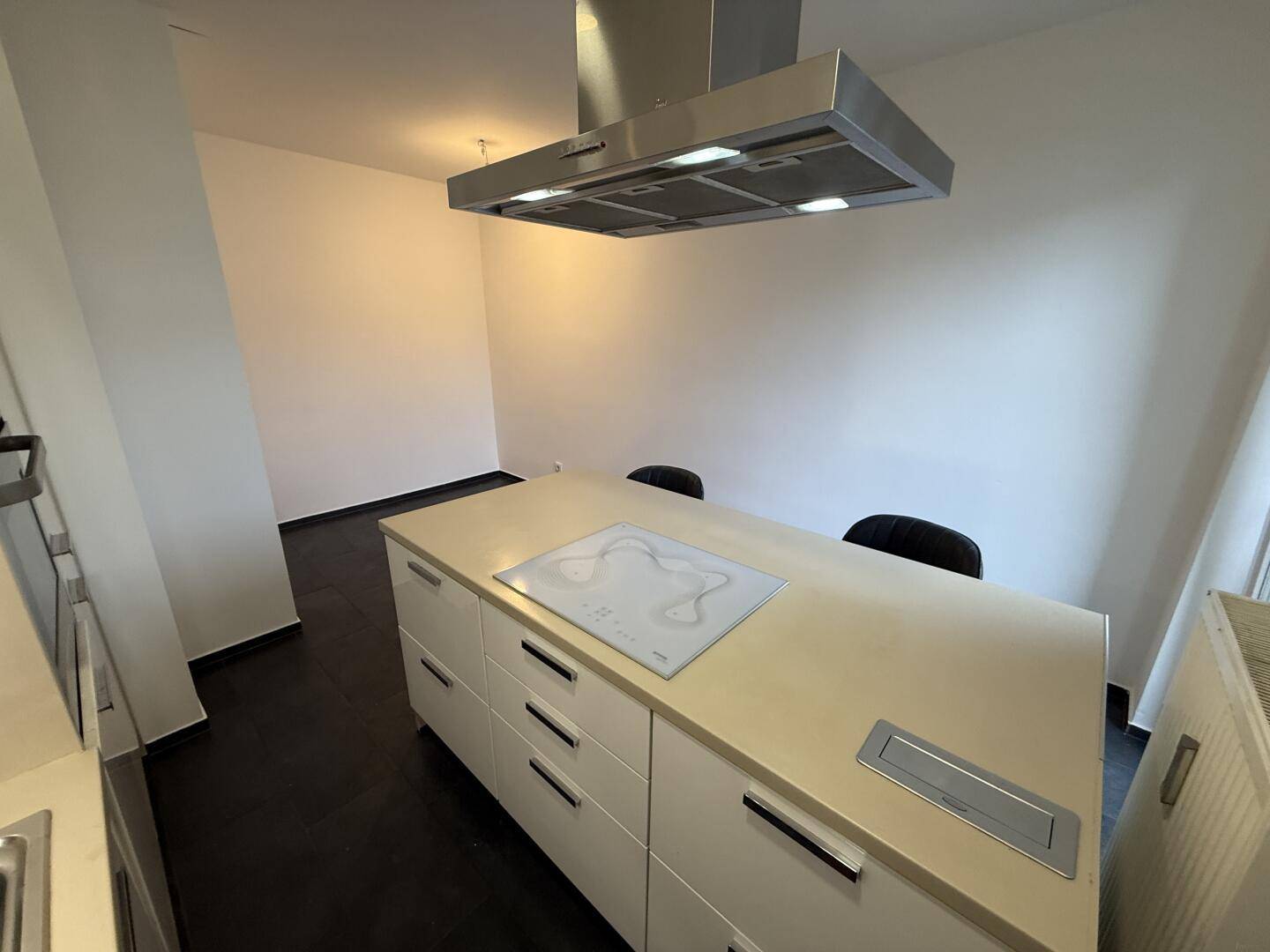 Moderne Kochinsel mit Induktionskochfeld und Dunstabzugshaube in offener Küche.