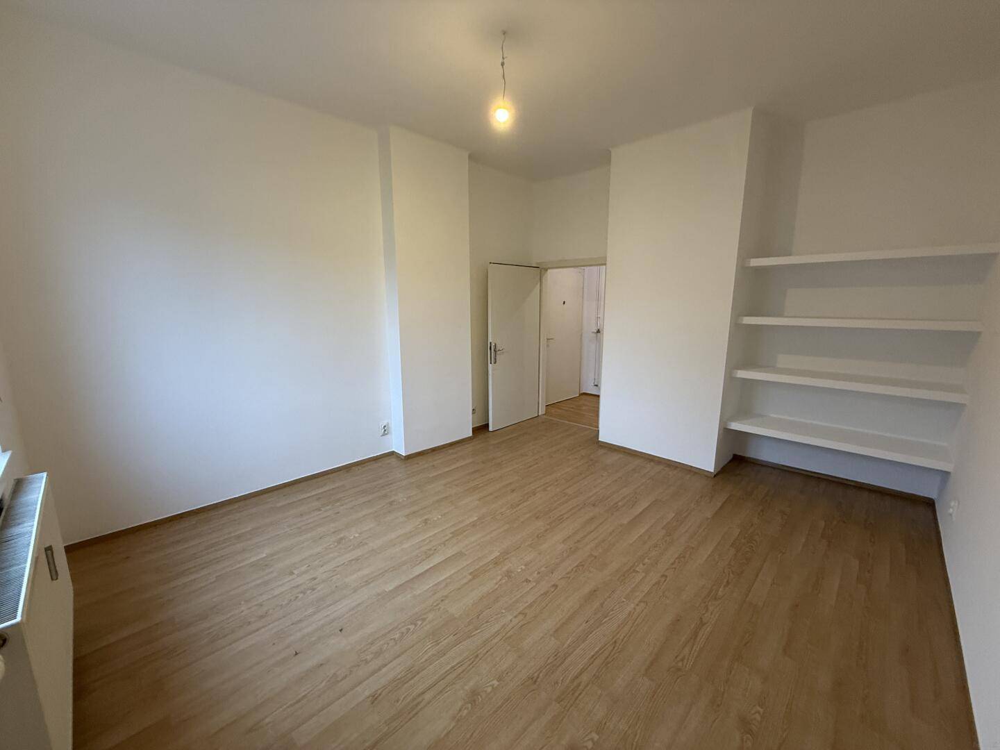 Leeres Zimmer mit Laminatboden und praktischen Einbauregalen, ideal für Stauraum.