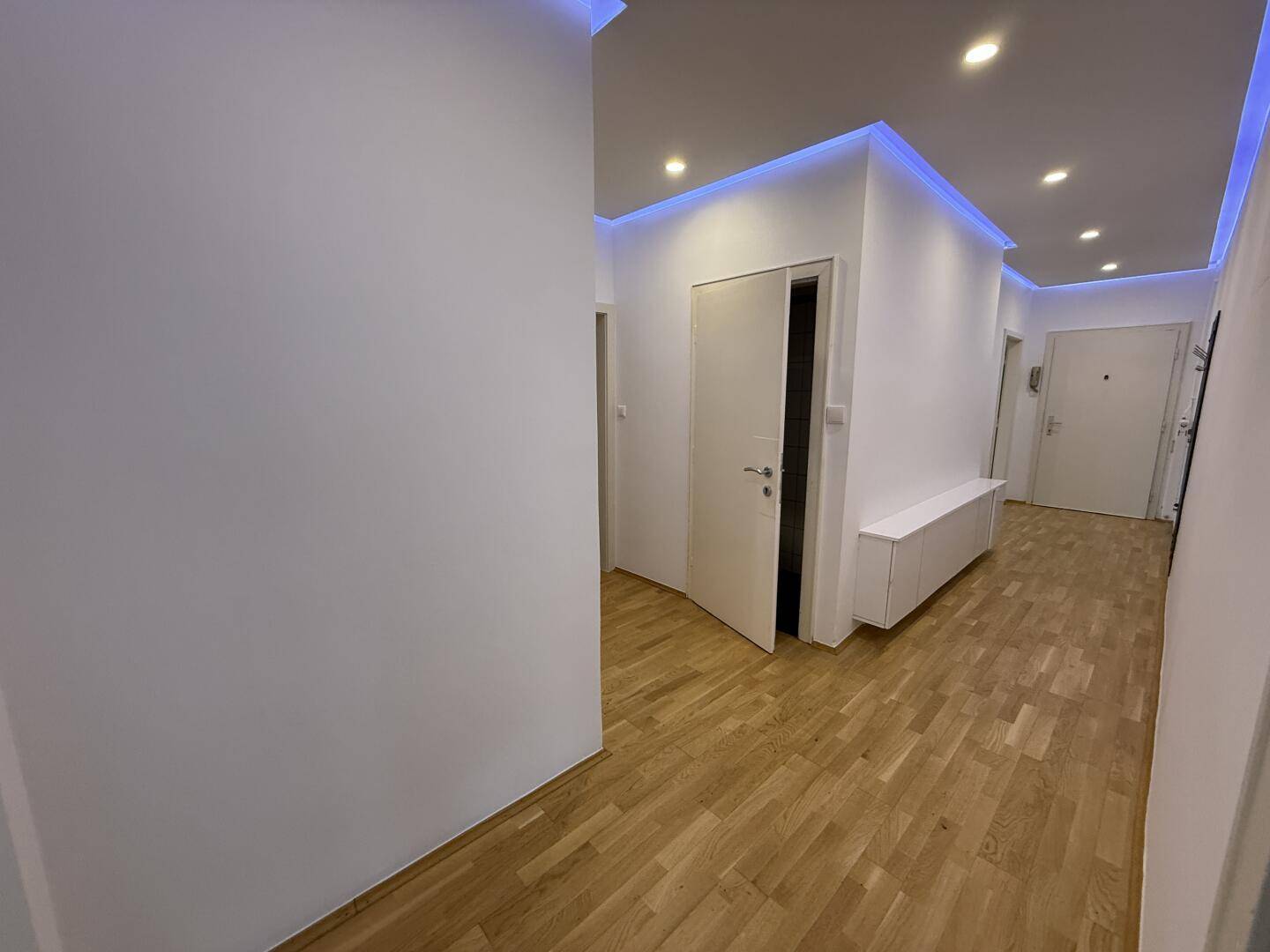 Moderner Flur mit Holzparkett und indirekter blauer LED-Beleuchtung an der Decke.