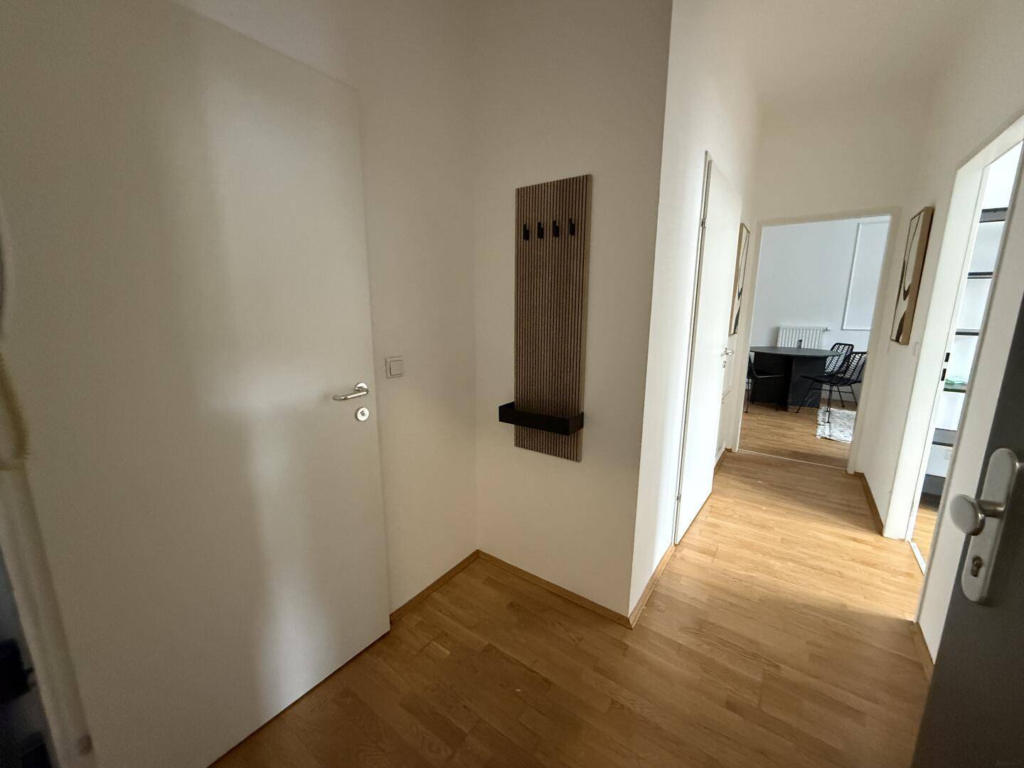 Eingangsbereich mit Holzboden, Garderobe und Zugang zu verschiedenen Zimmern.