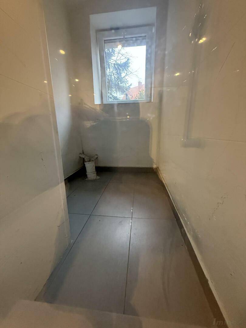 Leerer Raum im Badezimmer mit Fenster und Fliesenboden, bereit für Installationen.