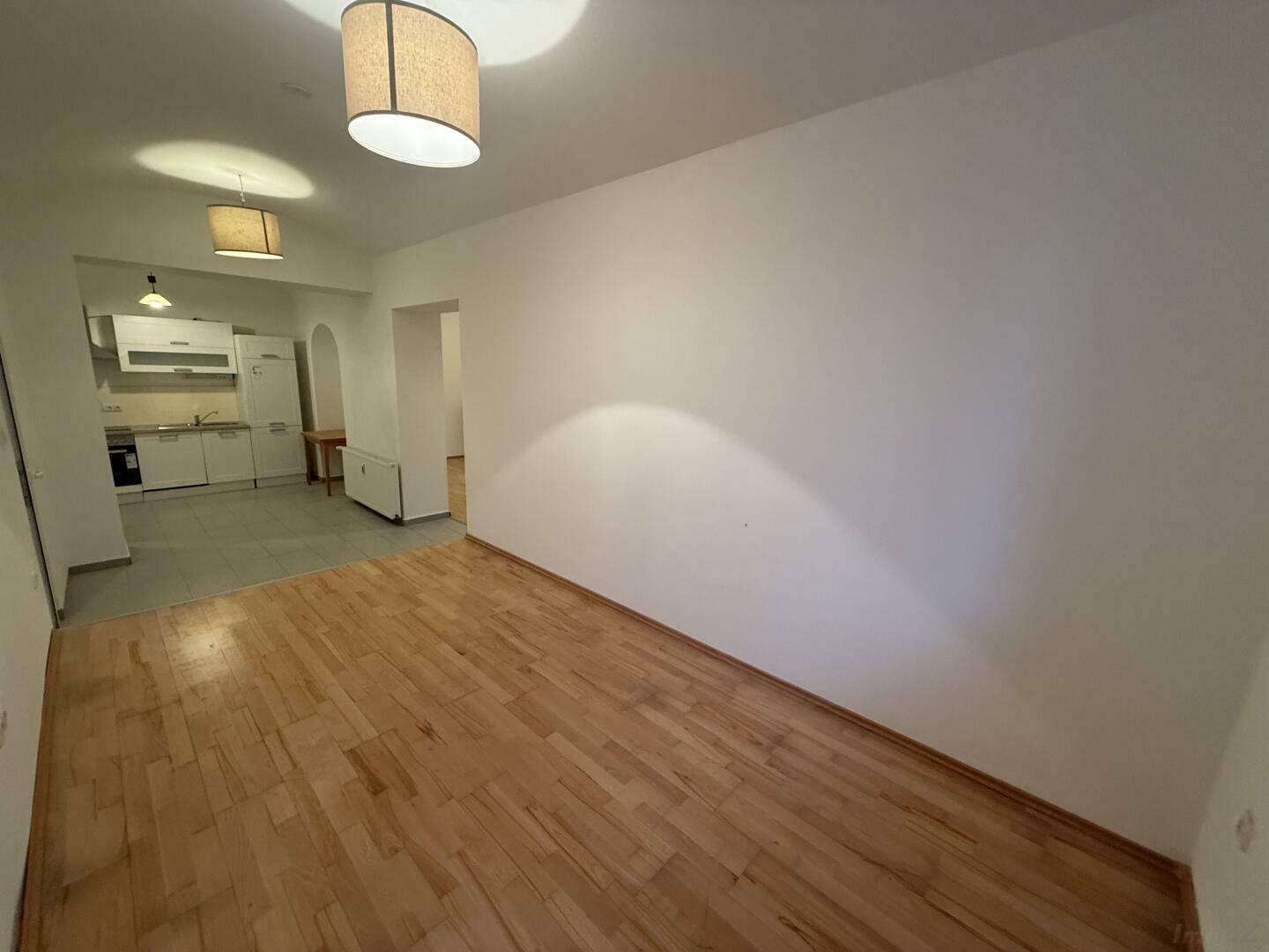 Heller Wohnbereich mit Parkettboden und offener Küche, ideal für modernes Wohnen.