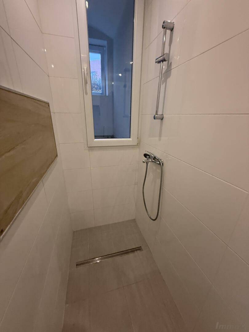 Duschbereich im Badezimmer mit Fliesen und Fenster, hell und funktional gestaltet.