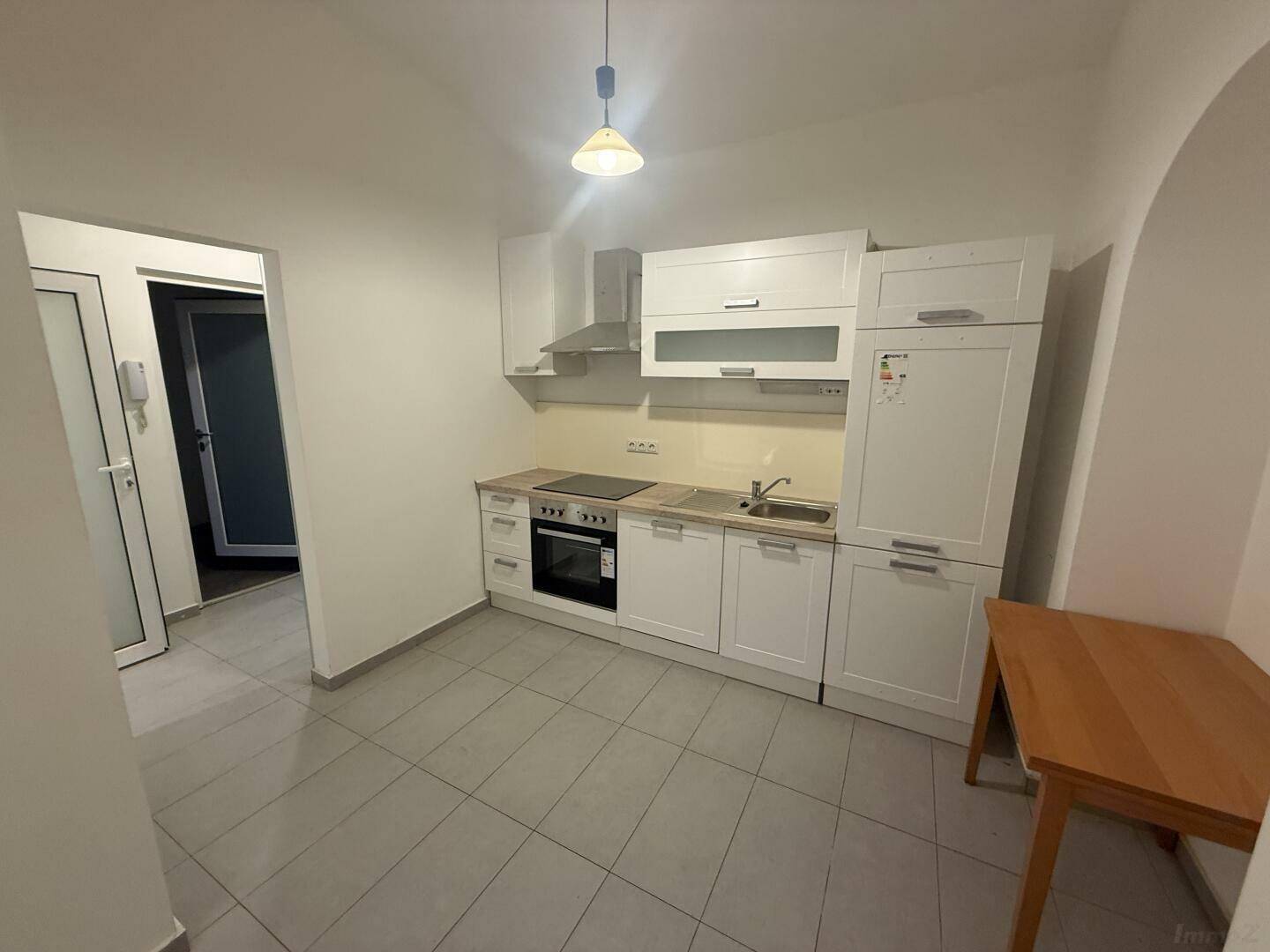 Moderne Einbauküche in Weiß mit Kochfeld, Backofen und Kühlschrank, funktional und hell.