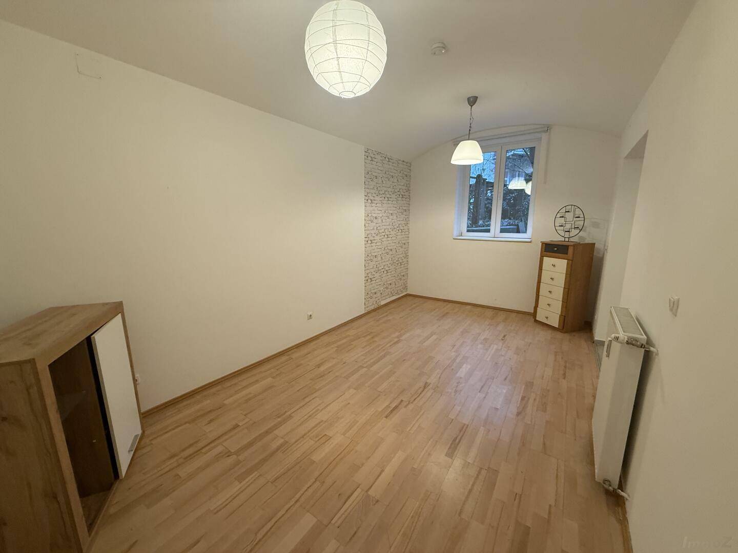 Heller Wohnraum mit Parkettboden, Fenster und moderner Einrichtung, einladend und gemütlich.