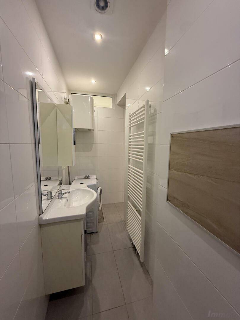 Helles Badezimmer mit Waschbecken, Spiegel und Handtuchheizkörper, modern gefliest.