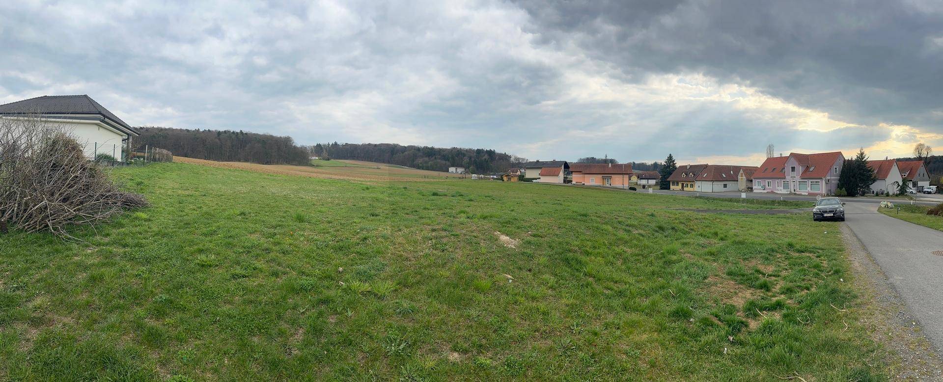 Weitläufiges Wiesengrundstück neben einer Straße mit Blick auf die umliegende ländliche Bebauung.