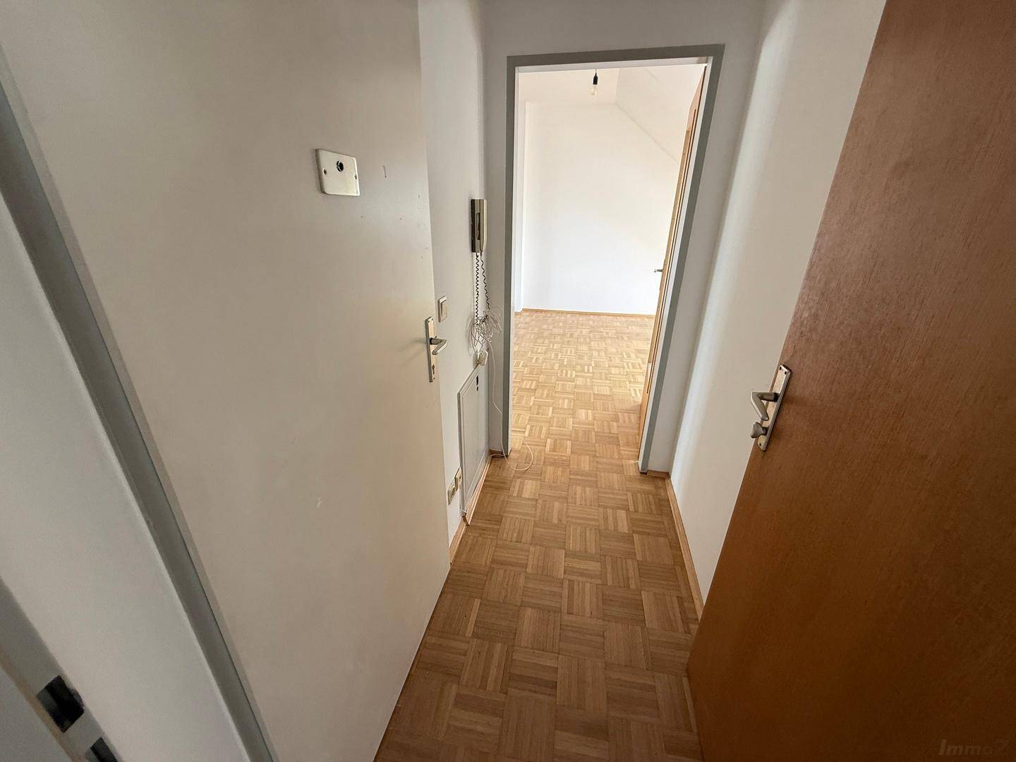 Schmaler Flur mit Parkettboden und weißen Türen, der zu weiteren Räumen führt.