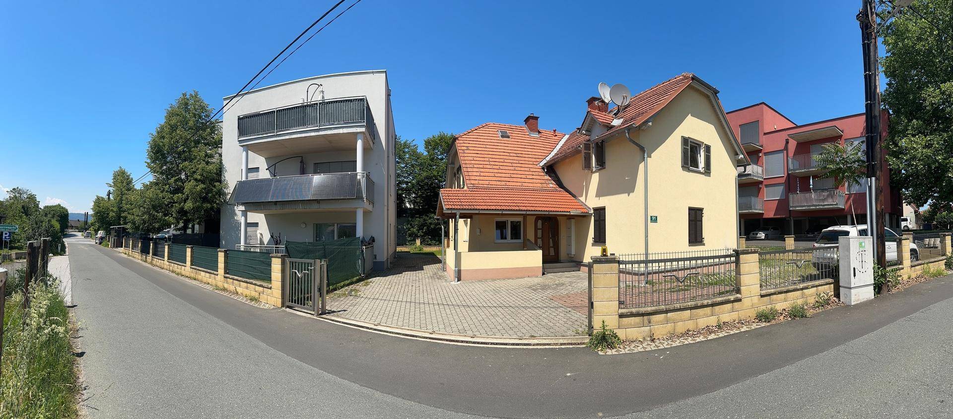 Panoramaansicht zweier Gebäude: ein traditionelles Haus und ein modernes Gebäude mit Balkonen.