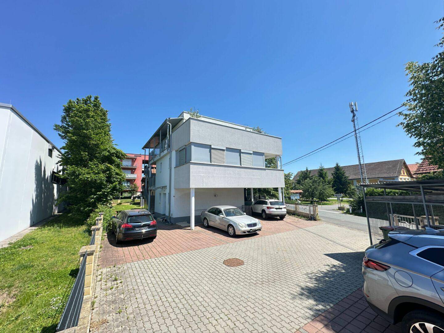 Weitwinkelansicht des modernen Gebäudes mit Parkplätzen und umliegender Grünfläche.