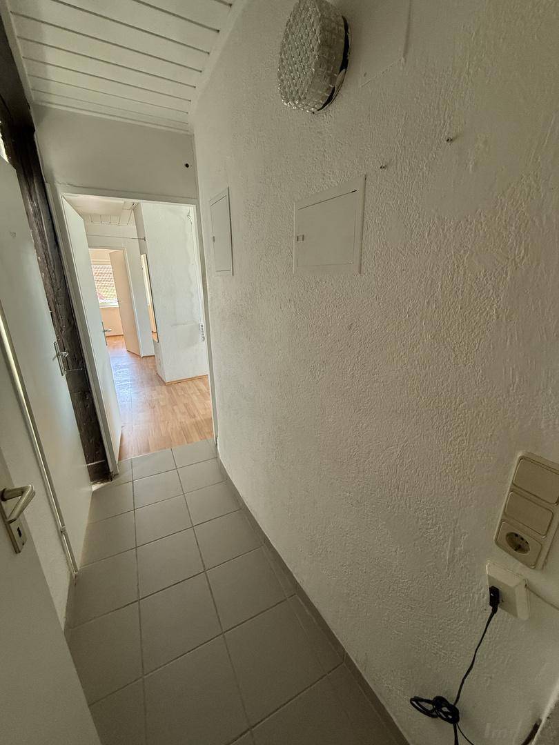 Schmaler Flur mit hellen Fliesen und Zugang zu weiteren Räumen der Dachgeschosswohnung.