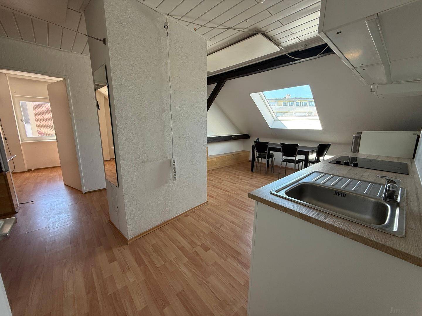 Offene Küche mit Spüle und Blick in den angrenzenden Wohnbereich der Dachgeschosswohnung.