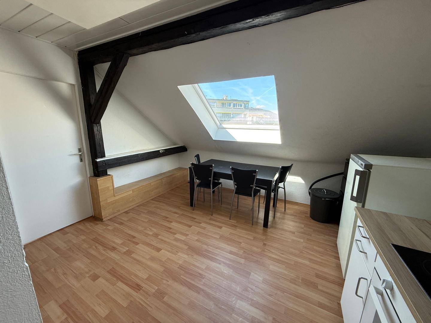 Heller Essbereich mit schwarzem Tisch und Stühlen, integriert in die offene Dachgeschossküche.