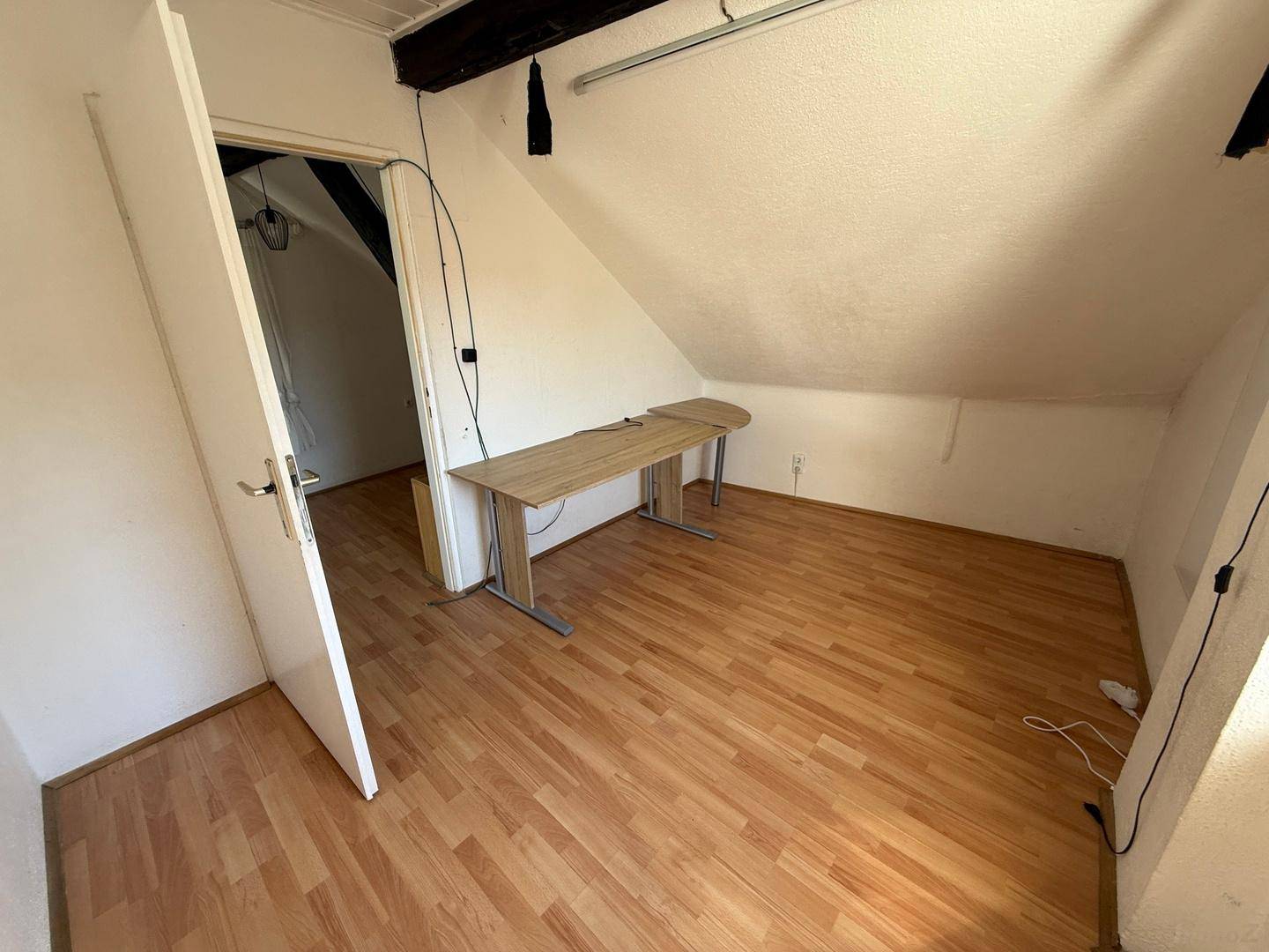 Geräumiges Zimmer im Dachgeschoss mit Schreibtisch und Laminatboden, ideal als Arbeitszimmer.