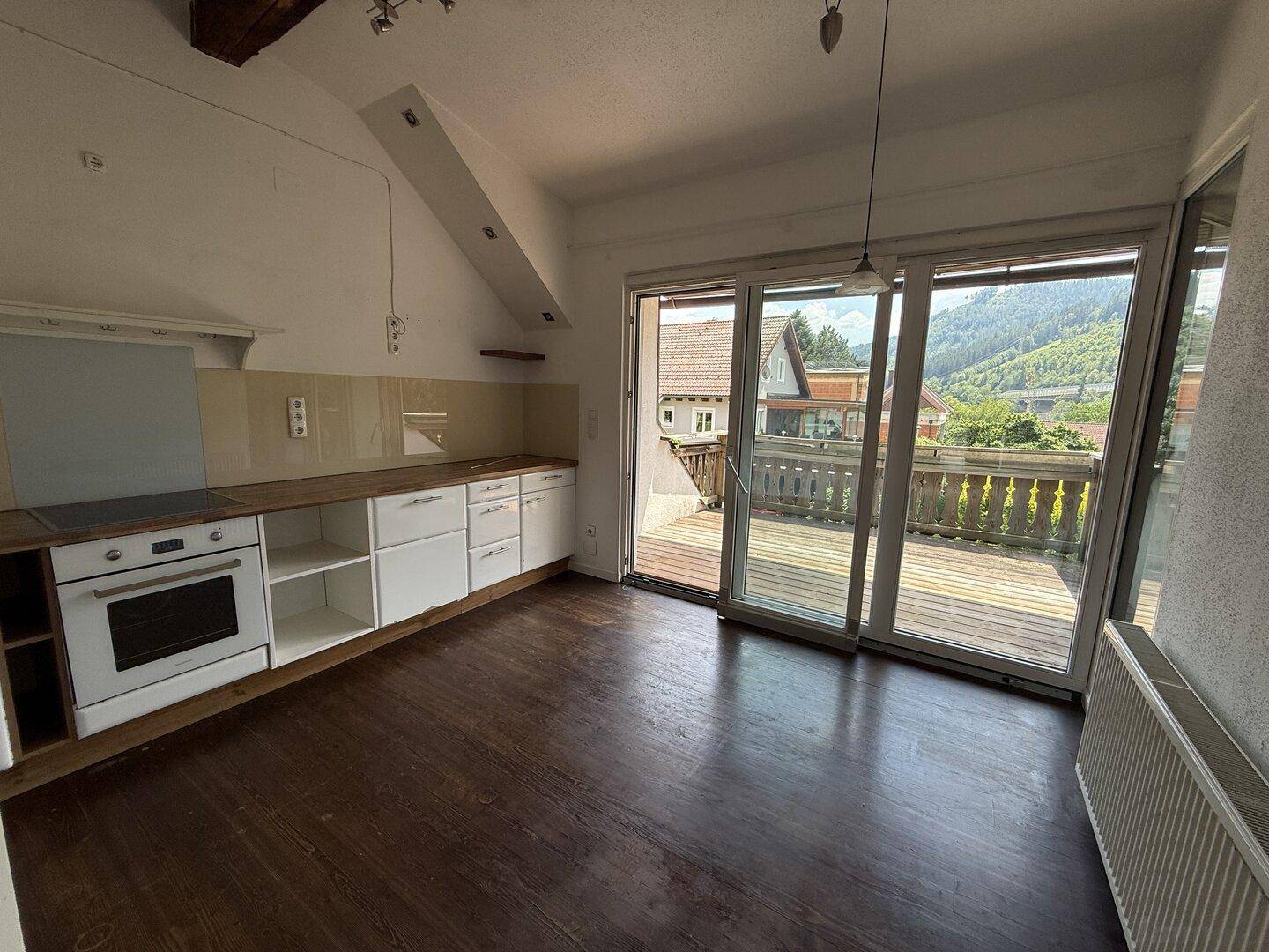 Helle Küche mit Einbauküche, Holzboden und Zugang zu einer großen Terrasse.