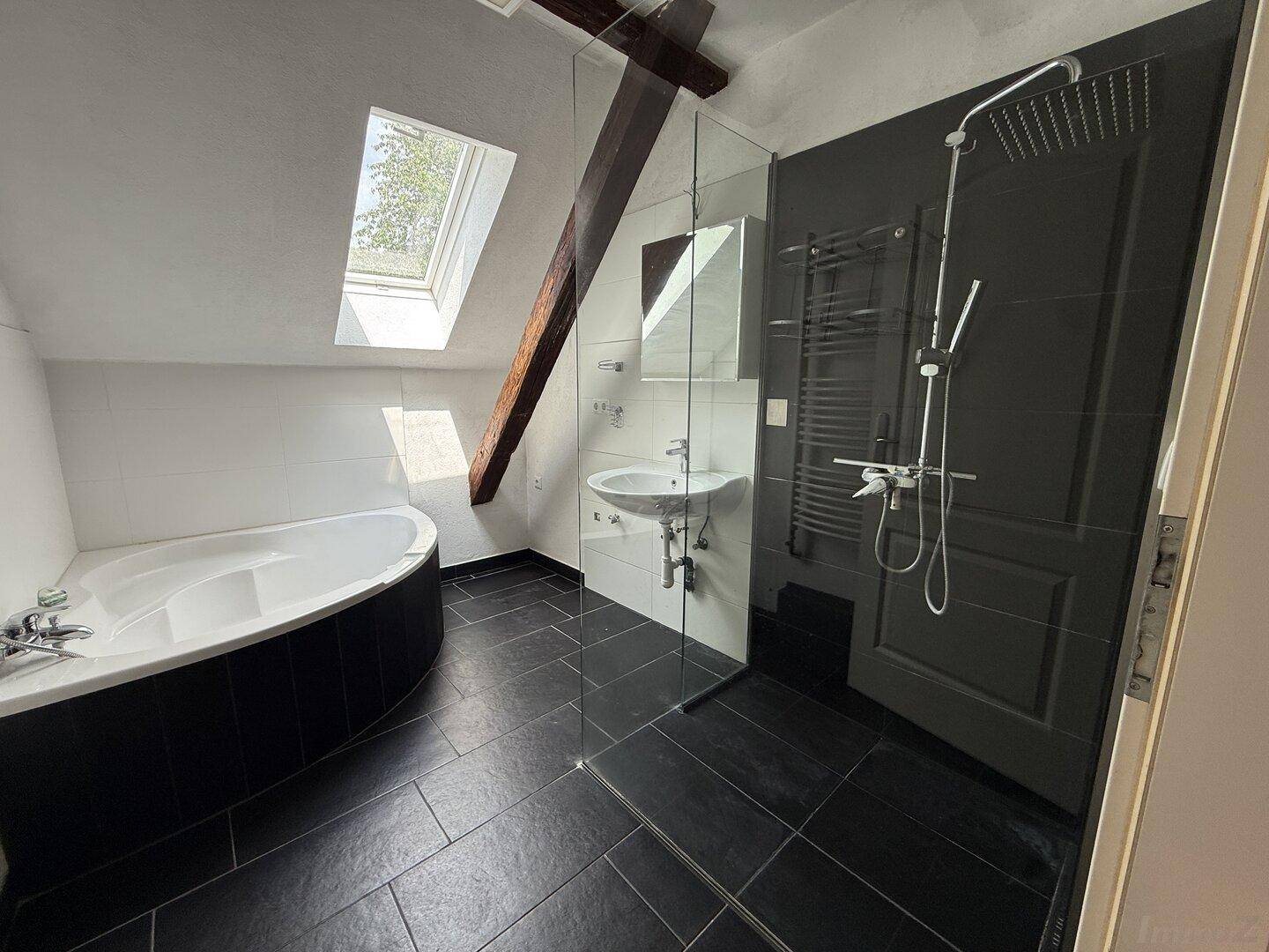 Modernes Badezimmer mit Eckbadewanne, begehbarer Dusche und Dachfenster.