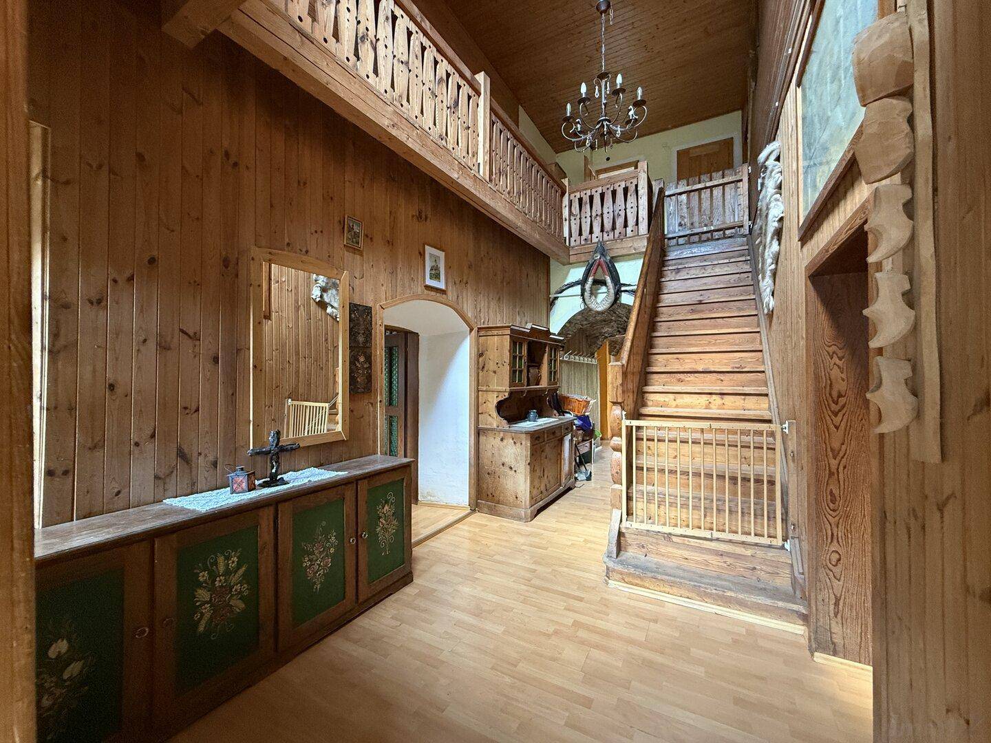 Traditioneller Eingangsbereich mit viel Holzvertäfelung, Treppe und Galerie im alpinen Stil.
