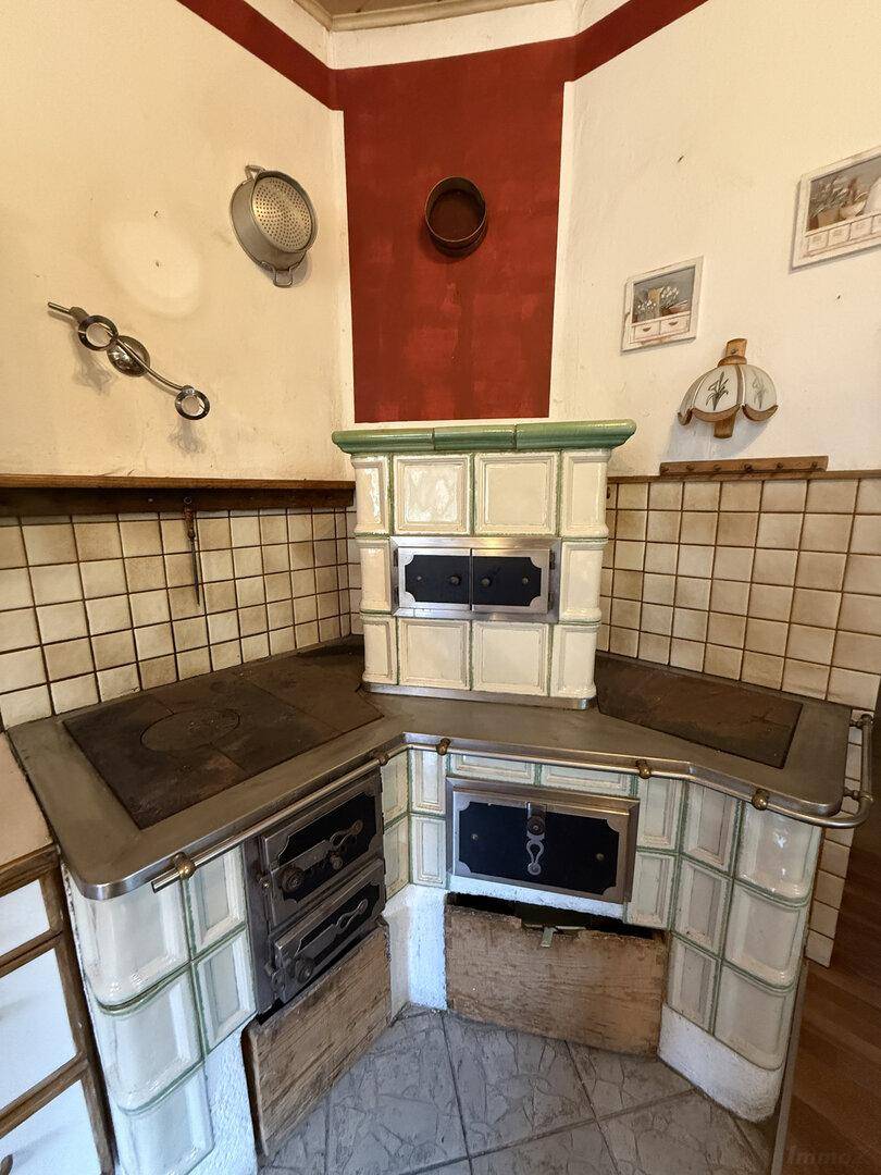 Rustikale Küche mit traditionellem Kachelofen und gefliesten Arbeitsflächen im Landhausstil.