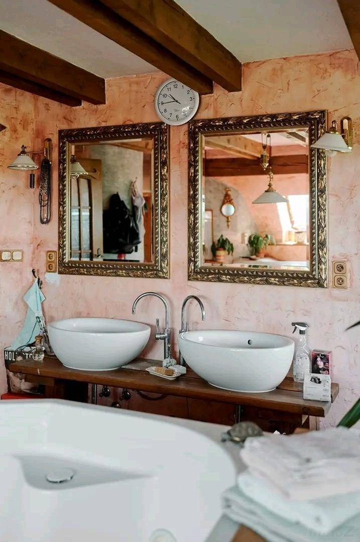 Badezimmer mit zwei Aufsatzwaschbecken, großen Spiegeln und Holzbalken an der Decke.