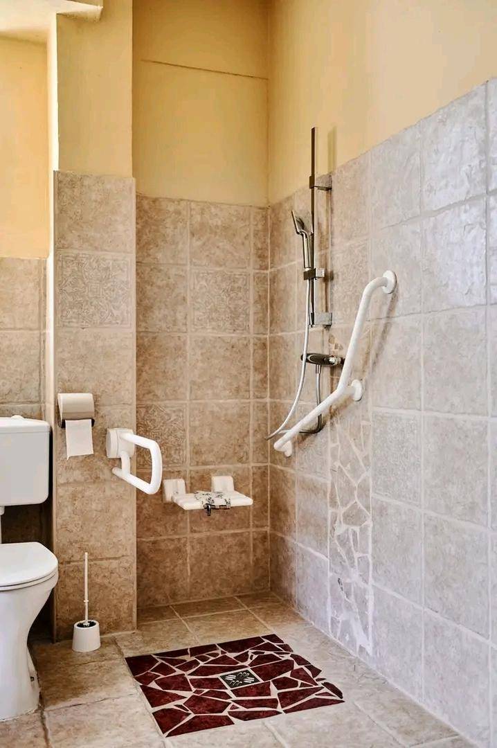 Barrierefreie Dusche mit Haltegriffen und einem Duschsitz in einem gefliesten Badezimmer.