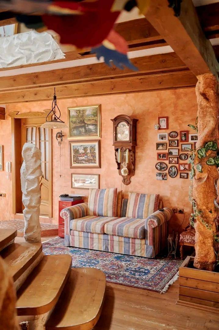 Gemütlicher Wohnbereich mit gestreiftem Sofa, Holzbalken und einer kunstvollen Baumstamm-Dekoration.