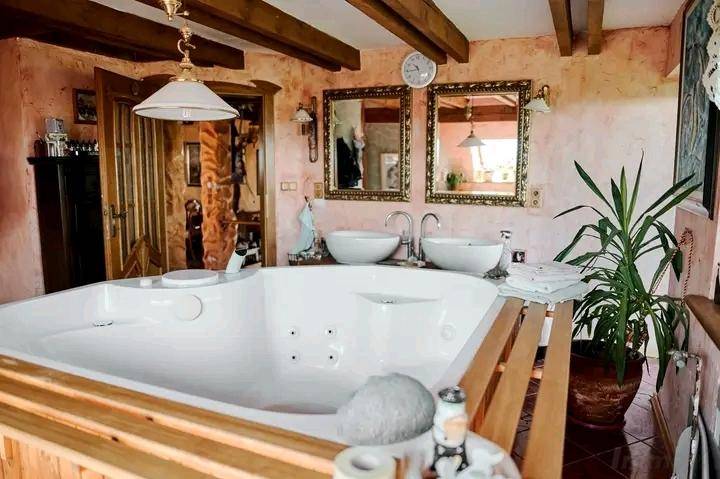 Geräumiges Badezimmer mit Whirlpool, zwei Waschbecken und Holzbalken an der Decke.