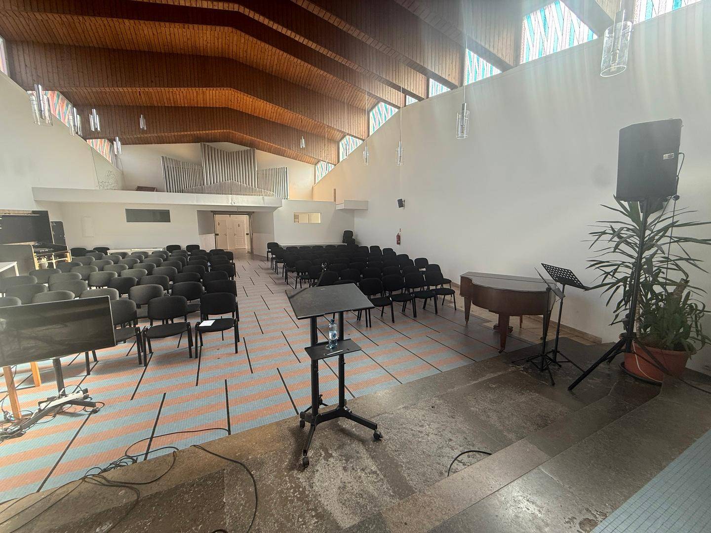 Blick durch den Saal zur Empore mit Orgel und weiteren Sitzgelegenheiten, einladend und funktional.