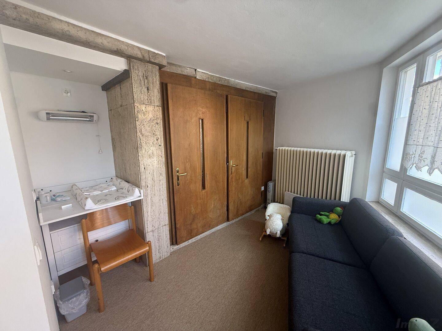 Raum mit Wickeltisch, Sofa und Einbauschränken, ideal als Kinderzimmer oder Mehrzweckraum.