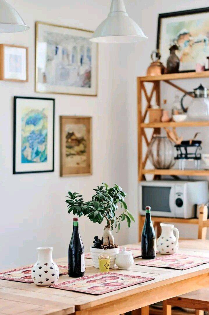 Heller Essbereich mit Holztisch, Bildern an der Wand und dekorativen Pflanzen.