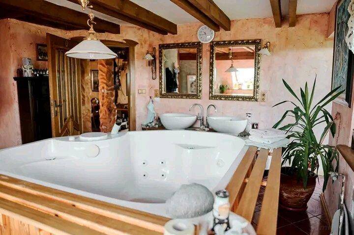 Geräumiges Badezimmer mit Whirlpool, Doppelwaschbecken und Holzbalken an der Decke.