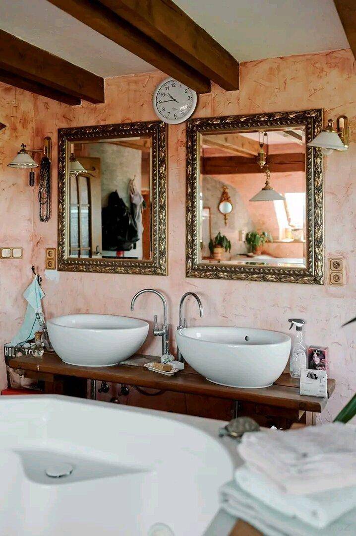Badezimmer mit Doppelwaschbecken, großen Spiegeln und rustikalen Holzbalken an der Decke.