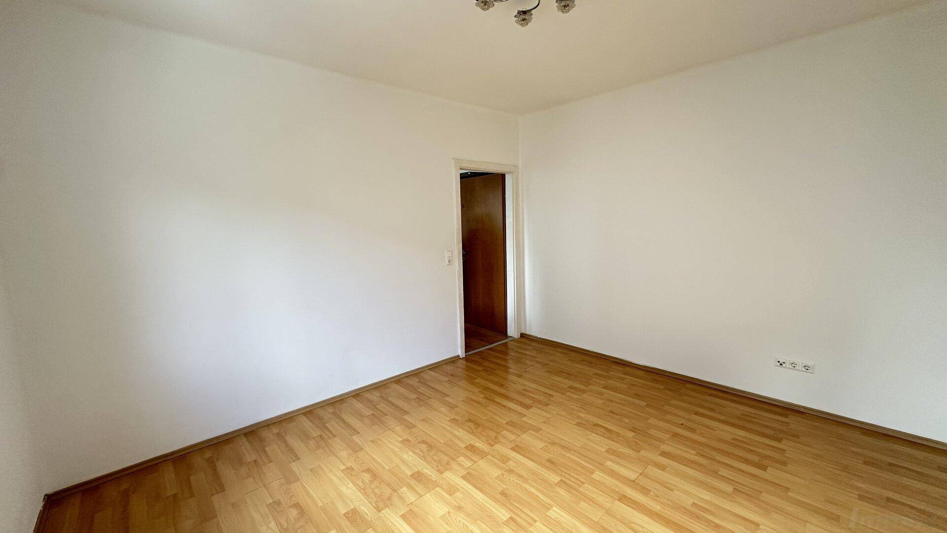 Leeres Zimmer mit hellem Parkettboden und weißen Wänden, bereit zur individuellen Gestaltung.