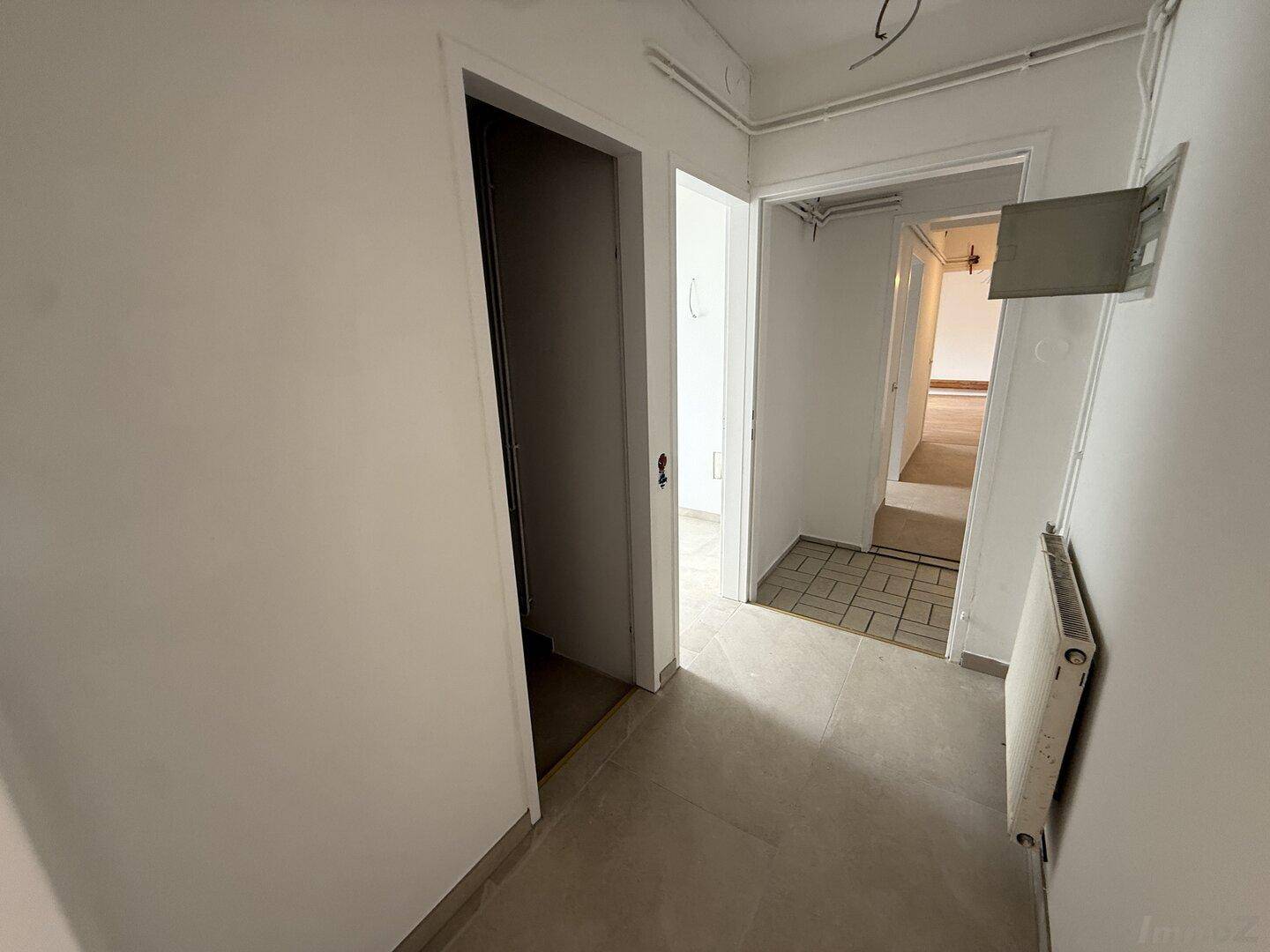 Heller Flur mit Fliesenboden und mehreren Türen, der verschiedene Bereiche der Wohnung verbindet.