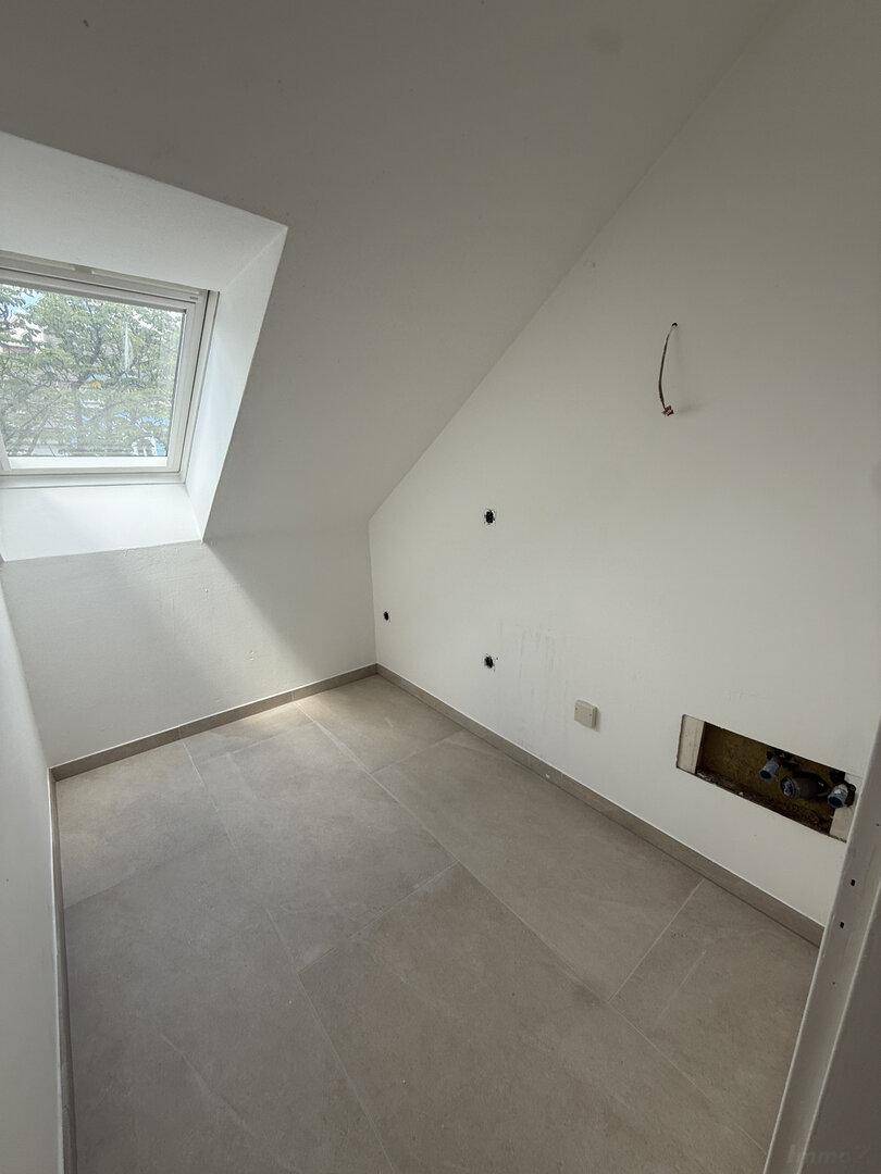 Kleiner Raum im Dachgeschoss mit Fliesenboden und Dachfenster, vorbereitet für weitere Installationen.