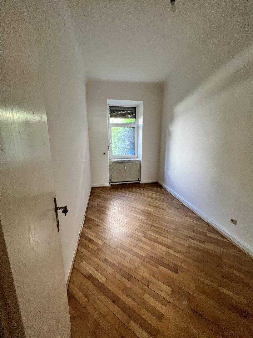 Kleineres, helles Zimmer mit Holzparkettboden und einem Fenster, geeignet als Schlaf- oder Arbeitszimmer.