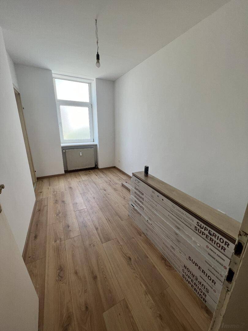 Zimmer mit neu verlegtem Laminatboden und einem Fenster, bereit für die Fertigstellung.