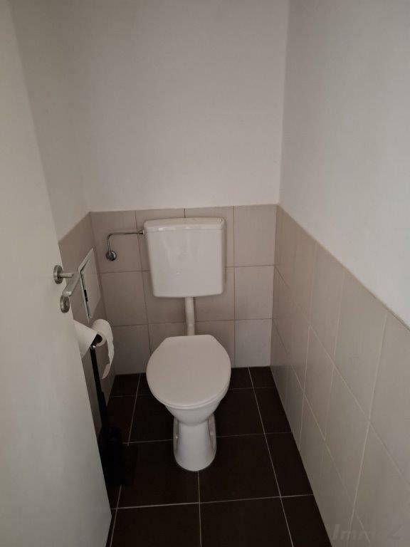 Separate Toilette mit WC und halbhohen Fliesen, einfach und funktional.