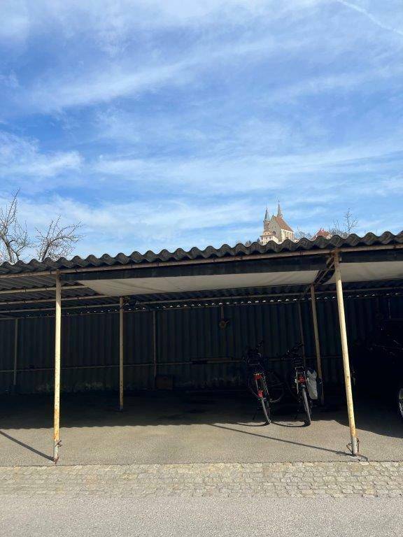 Überdachter Carport-Bereich mit Fahrrädern und Blick auf eine Kirche im Hintergrund.