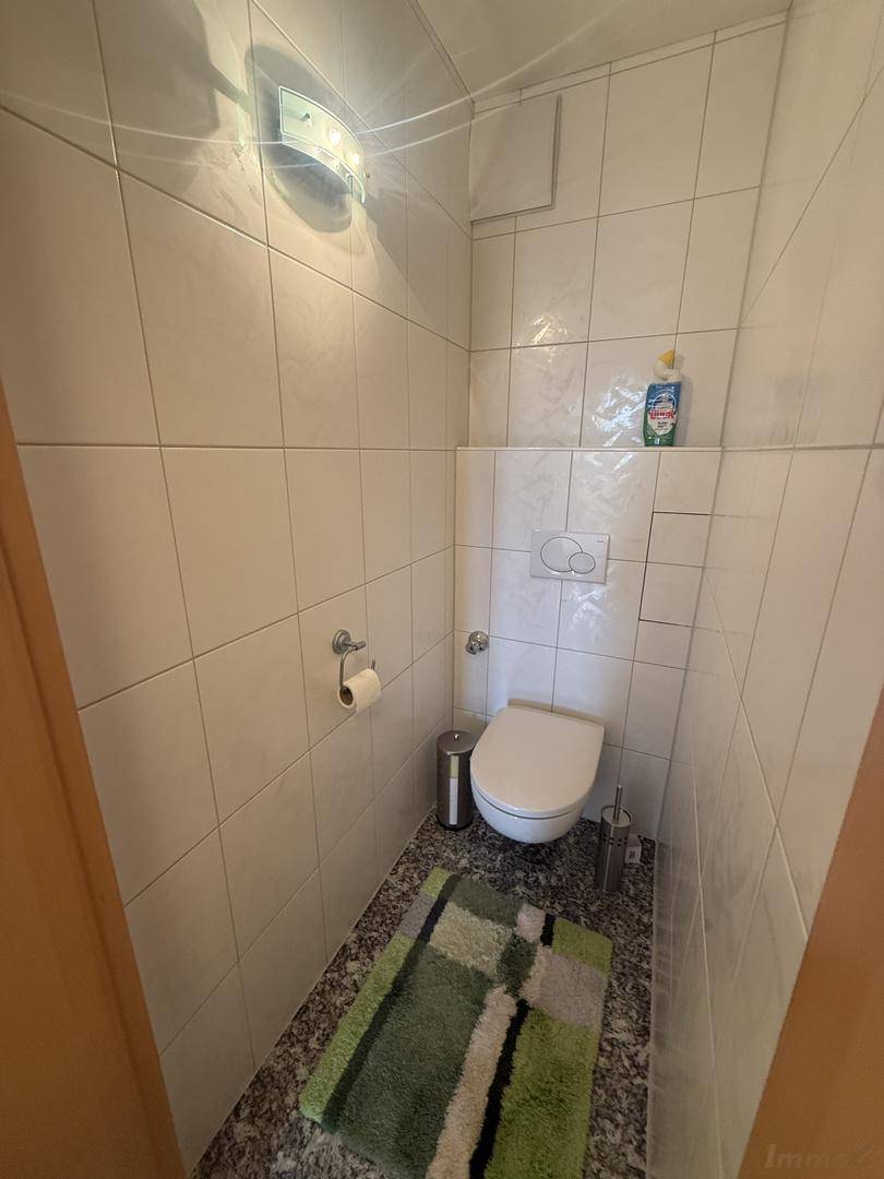 Kleines Gäste-WC mit weißen Fliesen an den Wänden und einem dunklen Granitboden.