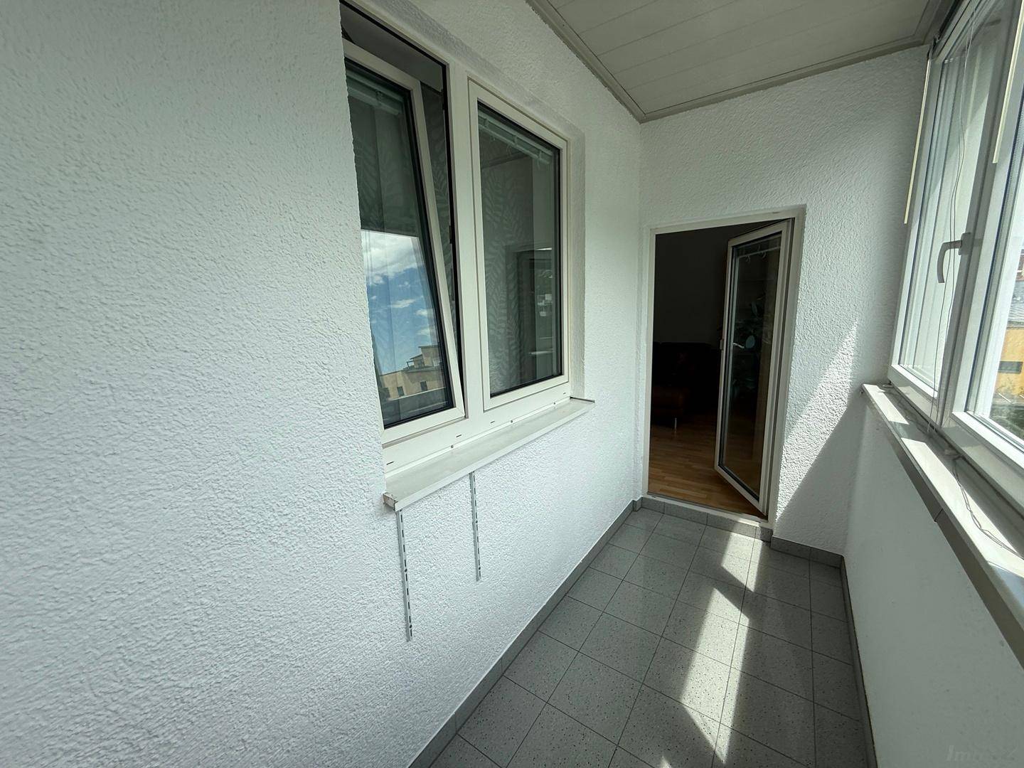 Geschlossener Balkon mit Zugang zum Innenbereich, ideal als sonniger Rückzugsort.