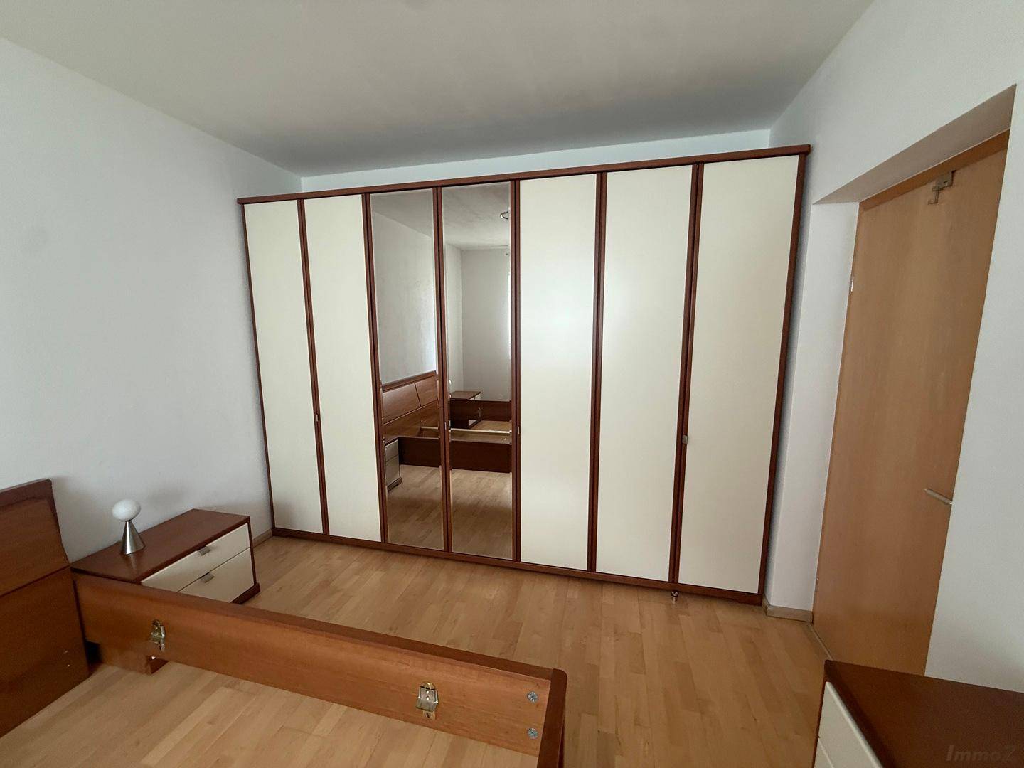 Großer Einbauschrank mit Spiegelfronten und hellen Türen im Schlafzimmer.