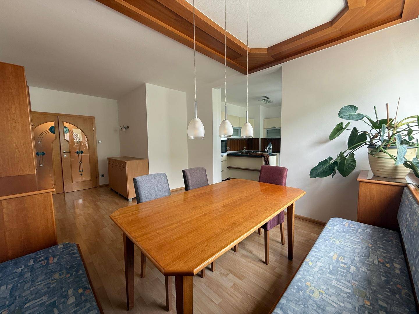 Gemütlicher Essbereich mit Holztisch und Blick auf die angrenzende Küche und Glastüren.