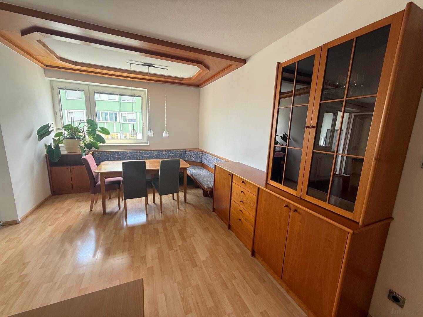 Geräumiger Essbereich mit Holztisch, Eckbank und passenden Holzschränken unter Deckenbalken.