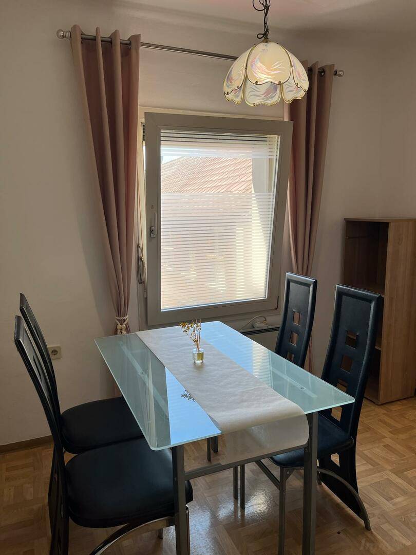 Gemütlicher Essbereich mit Glastisch, modernen Stühlen und Fenster mit Blick nach draußen.