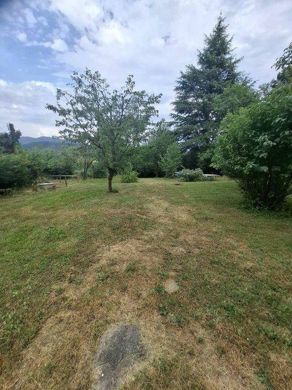 Offener Gartenbereich mit Bäumen und einem weiten Blick auf die umliegende Berglandschaft.